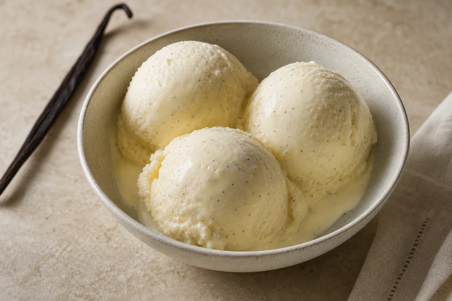 Silky vanilla bean ice cream with smooth scoops and visible vanilla seeds.