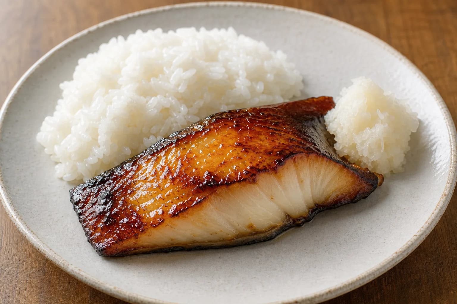 Miso-glazed black cod with lacquered gold-brown surface, moist white flakes, rice, and vinegared grated daikon.